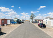 Thumbnail 1 of 4 - A residential street with houses on both sides and cars parked on the right side.