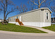 Thumbnail 4 of 8 - A small house with a grey roof and white siding.