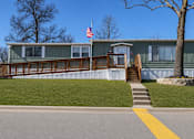 Thumbnail 3 of 8 - A house with a flag on the roof and a tree in front.