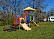 Thumbnail 6 of 8 - A playground with a yellow slide and a red and blue play structure.