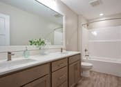 Thumbnail 1 of 10 - A bathroom with a white sink, brown cabinets at Ventura Townhouses, Apartments, West Olive  , MI