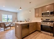 Thumbnail 3 of 10 - A kitchen with wooden cabinets and stainless steel appliances at Ventura Townhouses, West Olive  , Michigan