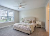 Thumbnail 8 of 10 - A bedroom with a large bed and a ceiling fan at Ventura Townhouses, Apartments, West Olive  , MI