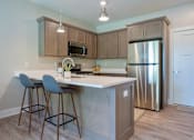 Thumbnail 4 of 10 - A kitchen with a stainless steel refrigerator and a bar area with two chairs at Ventura Townhouses, West Olive  