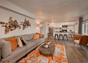 Thumbnail 38 of 41 - A living room with a grey couch and orange pillows