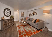 Thumbnail 36 of 41 - A living room with a grey couch, a wooden cabinet, a clock, and a rug