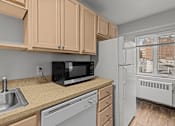 Thumbnail 16 of 41 - A kitchen with a black microwave, white fridge, and brown cabinets