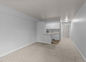Thumbnail 20 of 41 - A white room with a kitchenette and a carpeted before