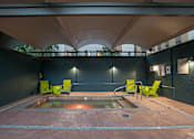 Thumbnail 9 of 41 - A hot tub is surrounded by four chairs in a room with a black wall