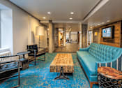 Thumbnail 3 of 41 - A blue couch sits in a room with a wooden table and a TV mounted on the wall
