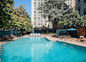 Thumbnail 8 of 41 - A swimming pool surrounded by trees and chairs.