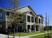 Thumbnail 10 of 22 - A person in a white coat is standing outside a two-story house.