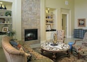 Thumbnail 8 of 22 - A living room with a fireplace and a floral patterned sofa.