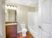 Thumbnail 6 of 22 - A white toilet sits next to a white bathtub in a bathroom.