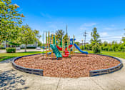 Thumbnail 3 of 22 - A playground with a red slide and green and yellow play structures.