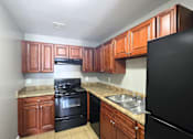 Thumbnail 13 of 17 - A kitchen with black appliances and wooden cabinets.