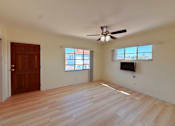 Thumbnail 4 of 12 - A room with a ceiling fan and a flat screen TV mounted on the wall.