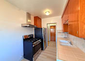 Thumbnail 5 of 12 - A kitchen with a black oven and wooden cabinets.
