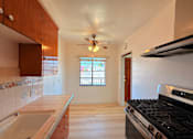 Thumbnail 6 of 12 - A kitchen with a stove, sink, and a window.
