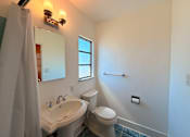 Thumbnail 10 of 12 - A white bathroom with a toilet, sink, and mirror.
