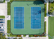 Thumbnail 8 of 21 - Two tennis courts surrounded by a green fence.