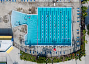 Thumbnail 7 of 21 - A large blue swimming pool with people in it.