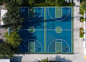 Thumbnail 9 of 21 - An outdoor basketball court surrounded by trees.