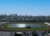 Thumbnail 21 of 21 - A view of a race track with a city skyline in the background.