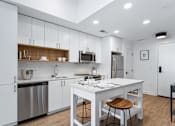 Thumbnail 7 of 34 - a white kitchen with a white island and stainless steel appliances