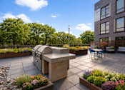 Thumbnail 3 of 34 - A patio with a table and chairs and a barbecue grill.
