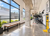 Thumbnail 4 of 51 - A brightly lit room with a bench, a potted plant, and a bike rack.