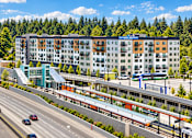 Thumbnail 1 of 51 - A modern multi-story building with a parking garage in front of it.
