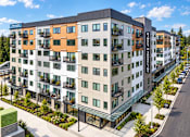 Thumbnail 2 of 51 - A modern apartment building with balconies and a green area in front.