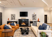 Thumbnail 3 of 14 - A living room with a fireplace and a television on the wall.
