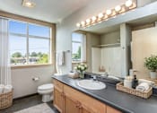 Thumbnail 11 of 14 - A bathroom with a large mirror and lights above it.