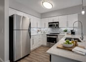 Thumbnail 6 of 14 - A modern kitchen with a stainless steel refrigerator and a marble countertop.