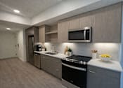 Thumbnail 3 of 30 - A modern kitchen with a black stove top oven and a microwave above the sink.