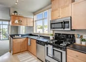 Thumbnail 13 of 14 - A kitchen with a black stove top oven and a black microwave above it.