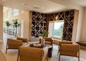 Thumbnail 28 of 30 - A living room with a large table surrounded by chairs and a wine rack in the background.