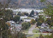 Thumbnail 12 of 12 - A view of a town from a hill with trees in the foreground.