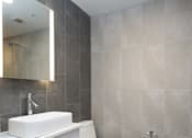 Thumbnail 4 of 20 - A white sink and toilet in a bathroom with grey tiles.