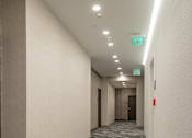 Thumbnail 18 of 20 - A long hallway with exit signs on the wall.