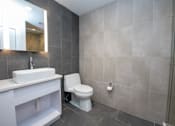 Thumbnail 14 of 20 - A bathroom with a toilet, sink, and mirror.