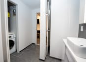Thumbnail 13 of 20 - A bathroom with a sink, toilet, and washing machine.