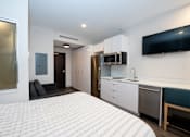 Thumbnail 15 of 20 - A modern bedroom with a large bed and a kitchenette.