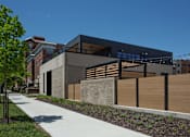 Thumbnail 42 of 51 - A modern building with a black facade and wooden fence.