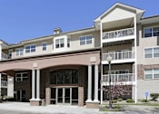 Thumbnail 32 of 37 - A large apartment building with a covered entrance and balconies.