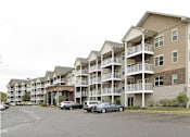 Thumbnail 36 of 37 - Apartment building with cars parked in front.