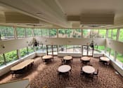 Thumbnail 10 of 37 - A large room with tables and chairs and windows overlooking a green lawn.
