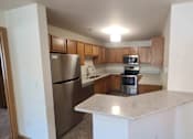 Thumbnail 15 of 37 - A kitchen with a refrigerator, microwave, oven, and stove.